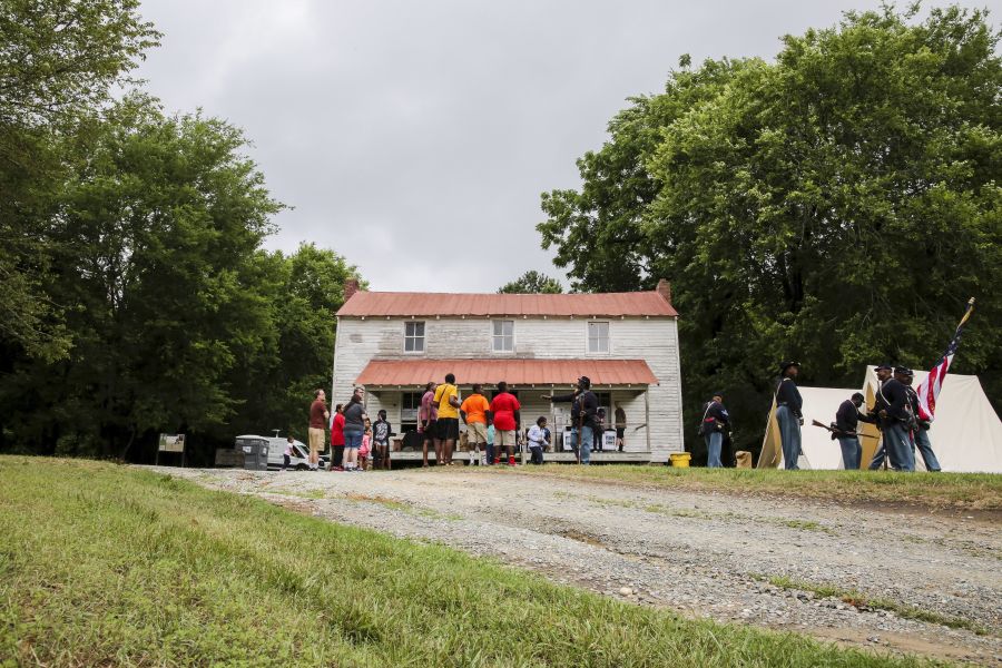 A group of visitors and re-enactors stand outside a building at Historic Stagville in Durham