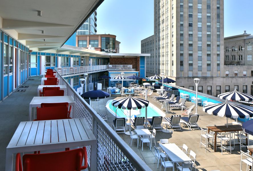 A balcony with tables overlooks the rooftop pool at Unscripted Hotel in Durham.