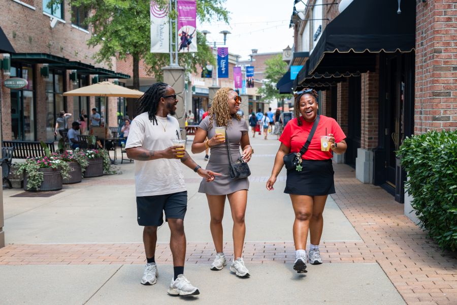 Three shoppers laugh and sip on beverages on the Streets at Southpoint.