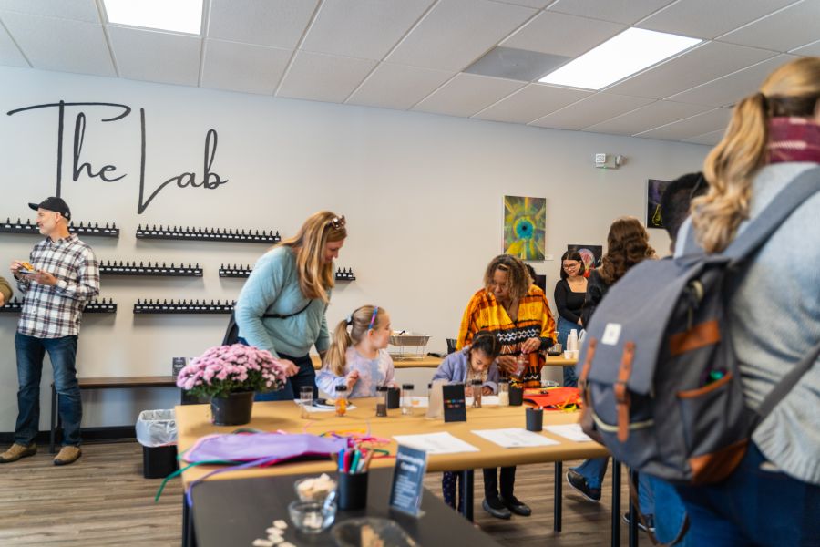 Participants blend scents at a table at Bright Black in Durham, with a wall of scents called "The Lab" in the background.