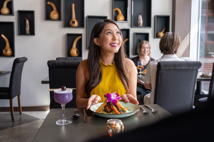 A customer sits with a colorful plate and cocktail at Zweli's Ekhayain Durham, NC.