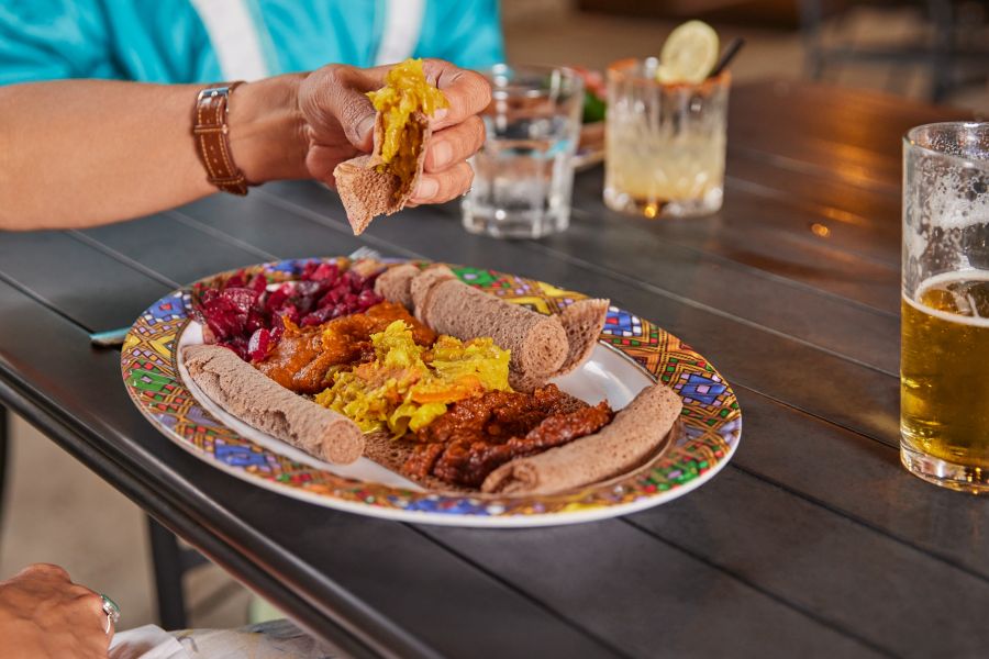 A hand lefts food up from a plate of food at Goorsha in Durham, NC.