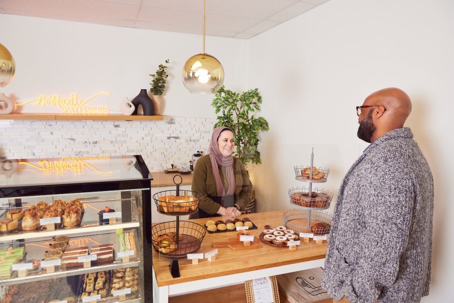 A man orders at a bakery counter where there are sweets in a bakery case.