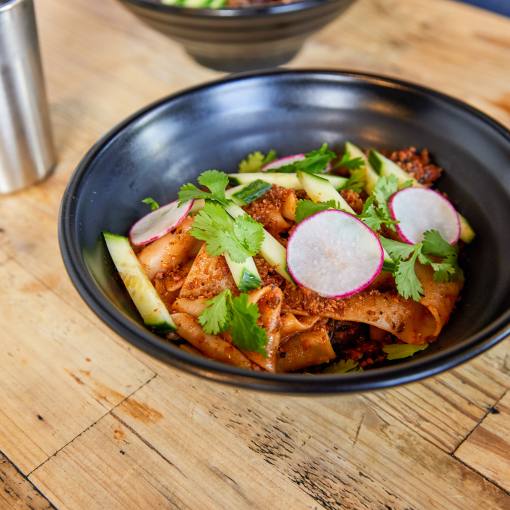 A plate of vegan Biang Biang noodles sits on a table at M Kokko waiting to be enjoyed.