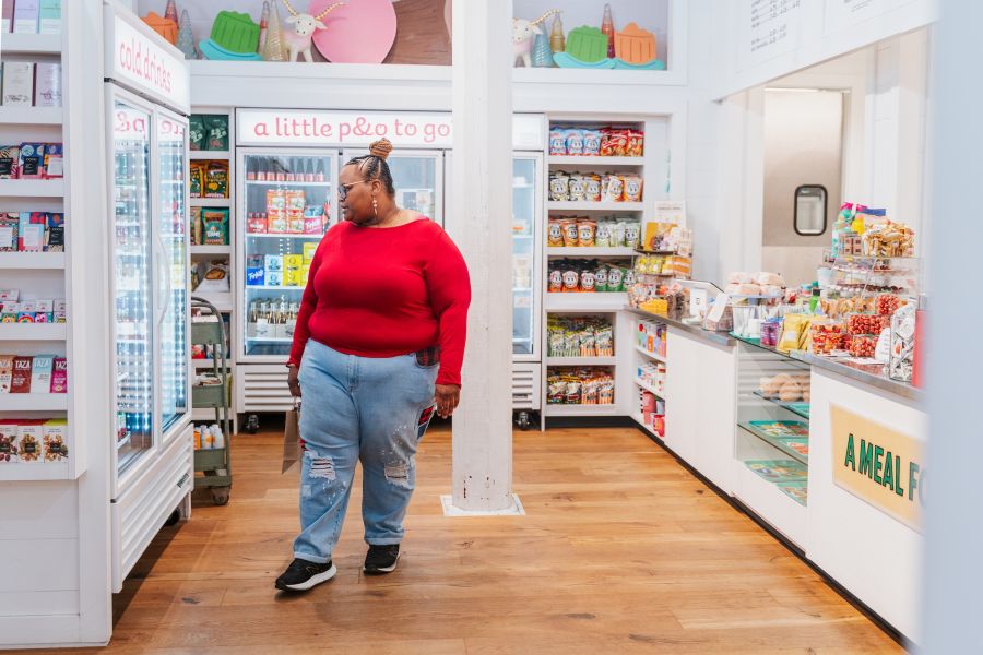 A patron in a red shirt and jeans peruses the goods behind a cooler at Parker and Otis.
