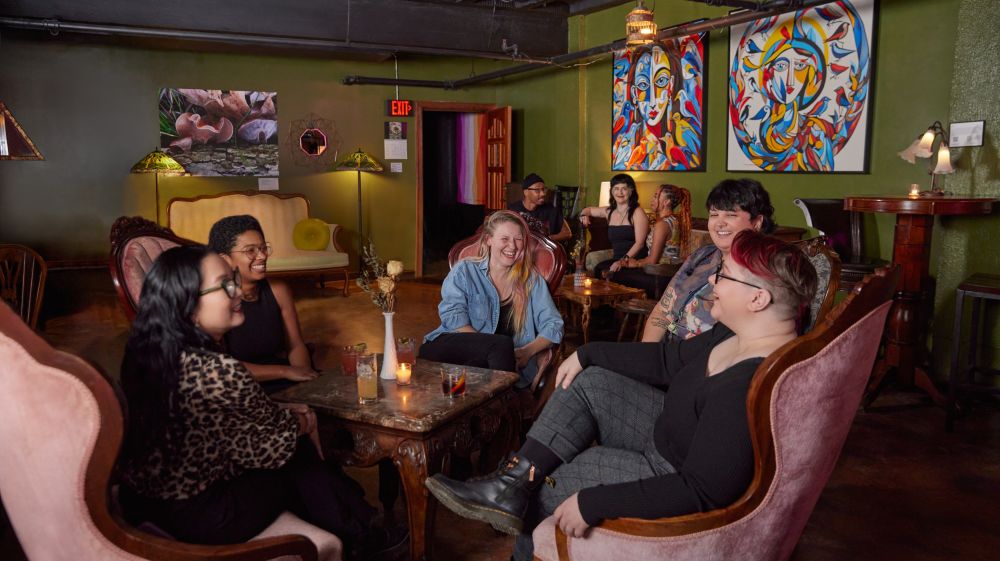 A group of friends sit around chairs at Arcana in Durham, NC.