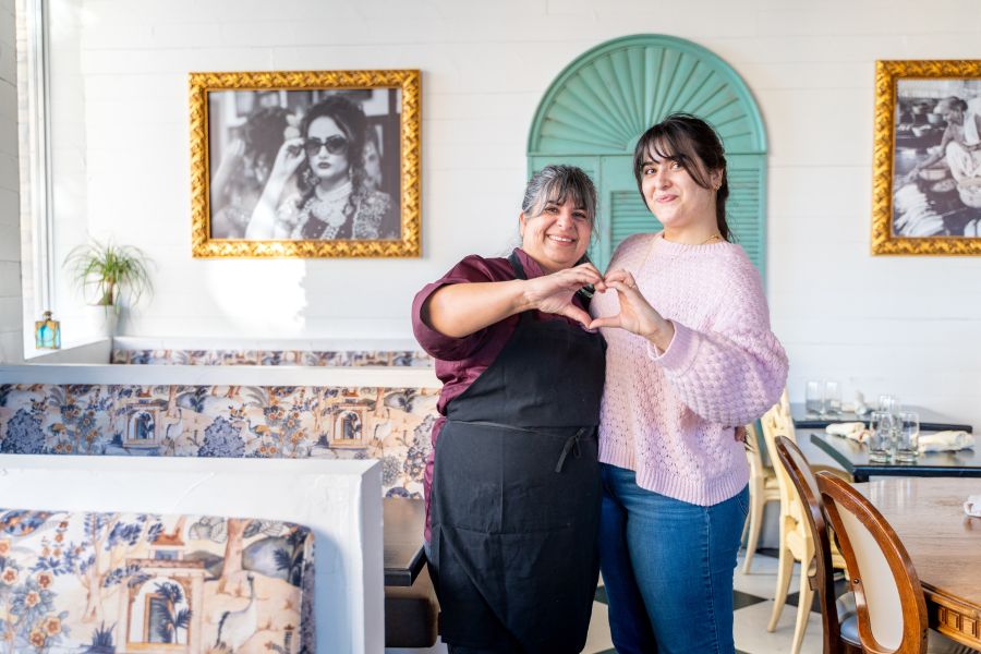 Cheeni owner Preeti Waas and her daughter, Amy, hold up their hands in the shape of a heart in the dining area.