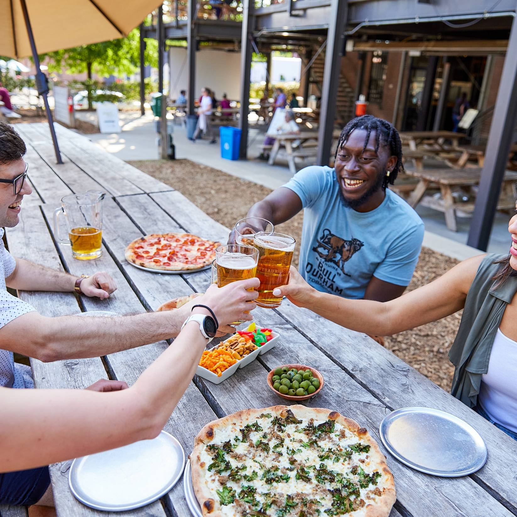 Friends cheers glasses over a table of snacks at Ponyaurus.