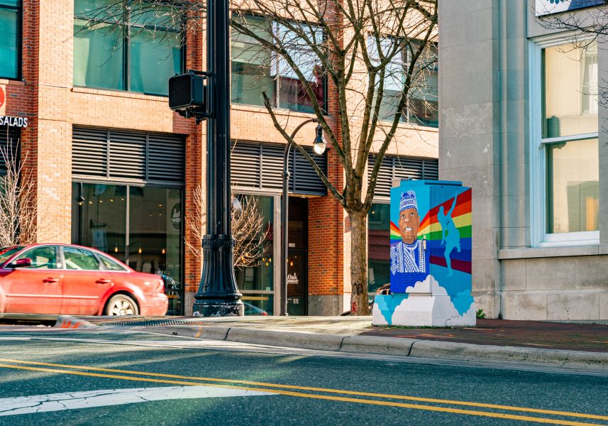 A car rounds the corner near the Baba Chuck mural in Downtown Durham.