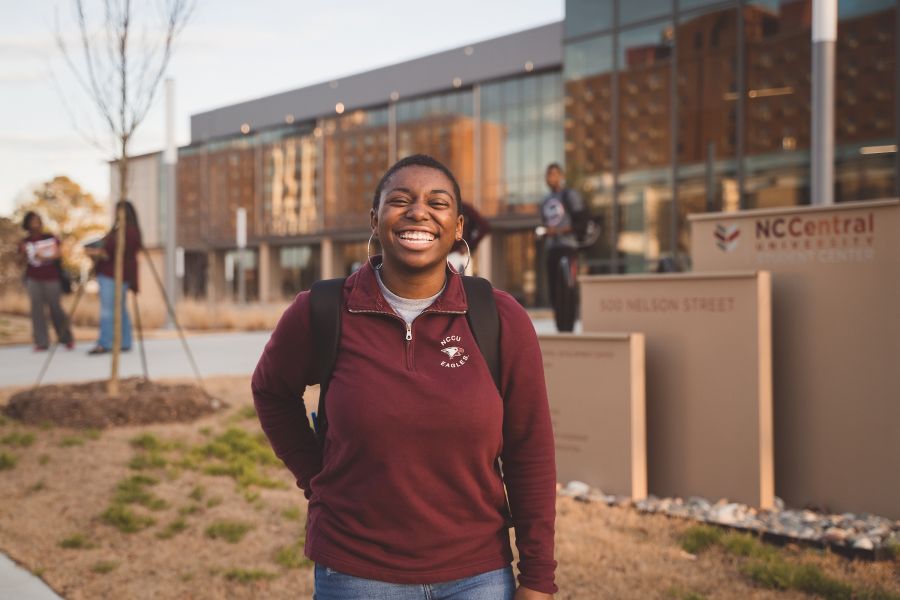 Portrait of an NCCU student smiling and laughing in front of the new student center.