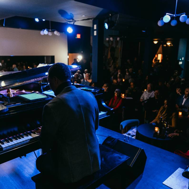 A pianist plays under blue lights for a crowd at Missy Lane's Assembly Room in Durham.