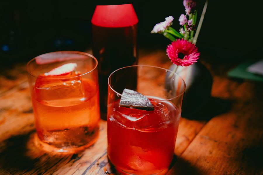 Two amber colored cocktails sit on a table next to a small vase of flowers at Kingfisher.