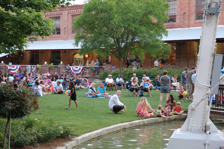 Visitors sit on the lawn at American Tobacco Campus in front of the man-made river.