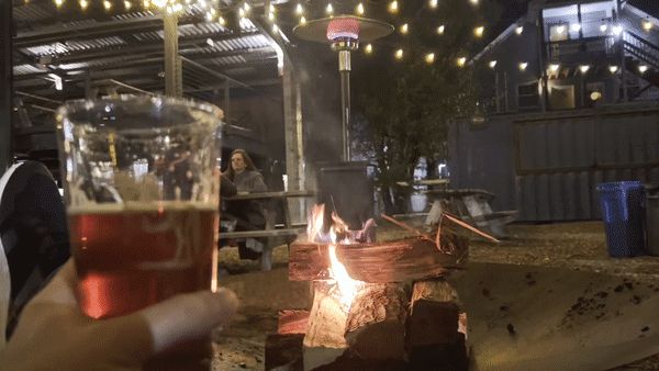 A person enjoys a beer while sitting by a fire pit at Durham's Ponysaurus.