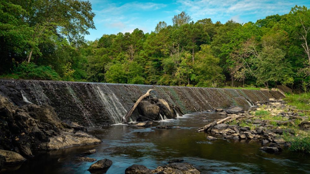 Water cascades over the dam at West Point on the Eno during a warm summer day.