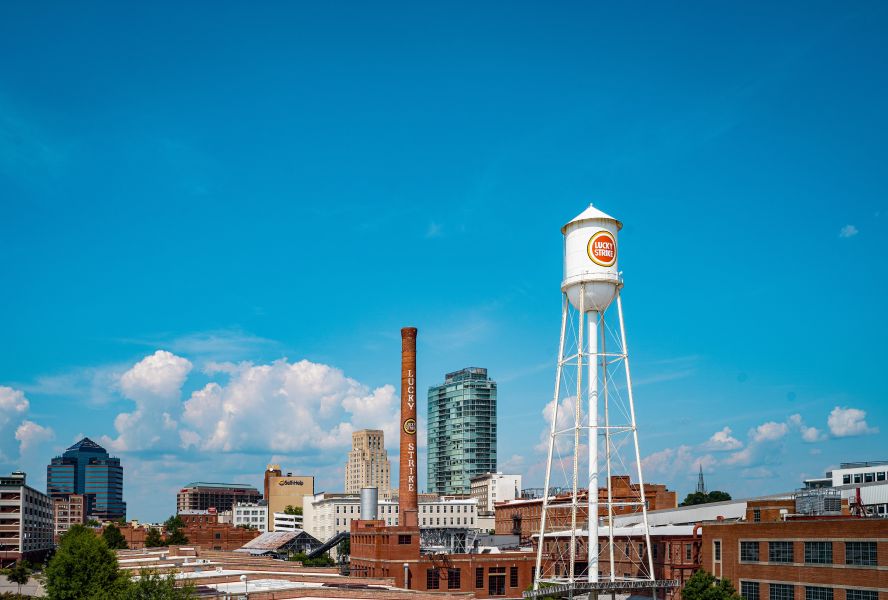 The Lucky Strike Tower stretches tall into a blue sky on the American Tobacco Campus.