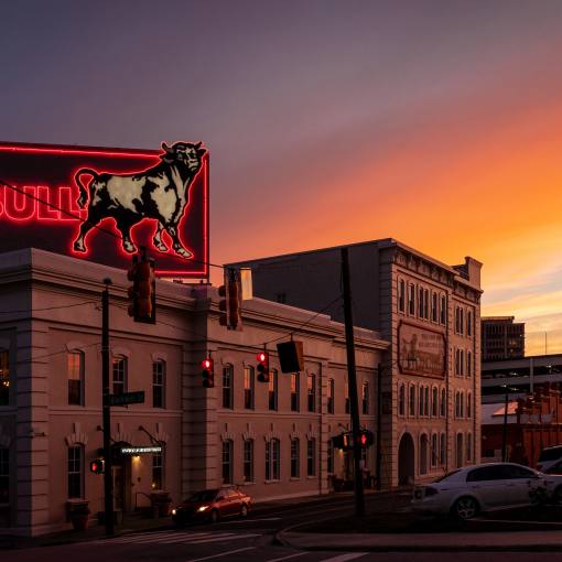 An orange and indigo sunset background the Old Bull sign in Durham, NC.