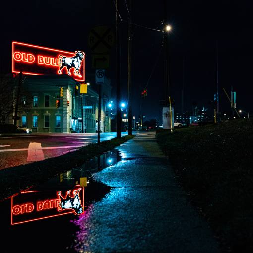 The streets of Durham are lit up at night by the neon Old Bull sign downtown after a rainy evening.