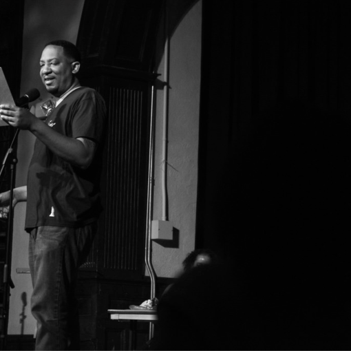 Durham author Dasan Ahanu reads on a stage.