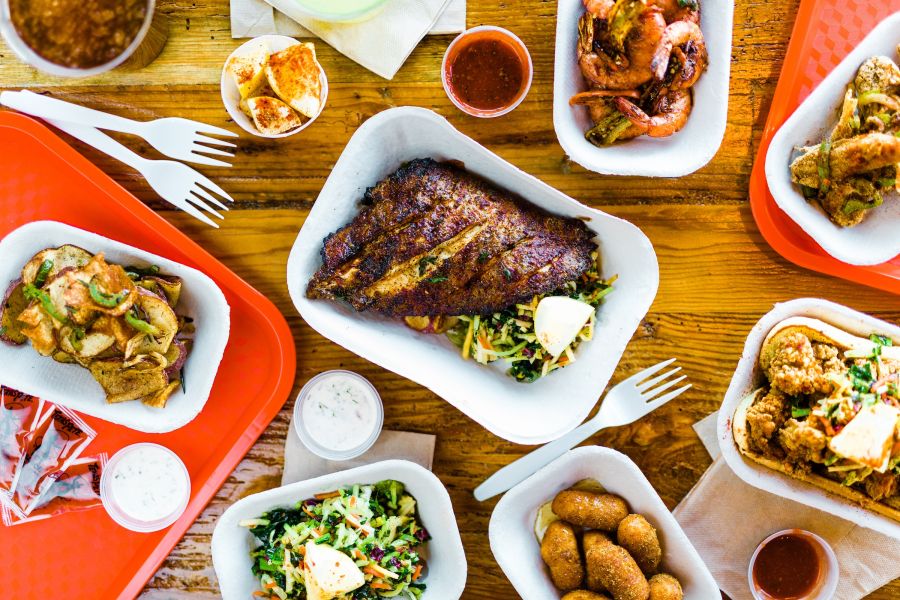An overhead photo of eight plates of seafood and vegetables from Saltbox Seafood Joint