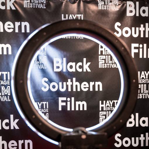 The Hayti Heritage Film Festival is the home of Black Southern film. A step and repeat with the film festival logo.