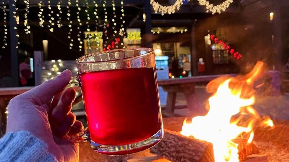 A glass of mulled wine is lit up by firelight at Ponysaurus brewing in Durham, NC.