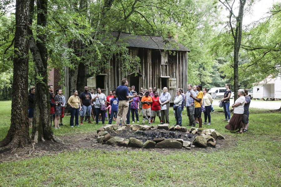 A tour guide speaks in front of an old building at Historic Stagville in Durham