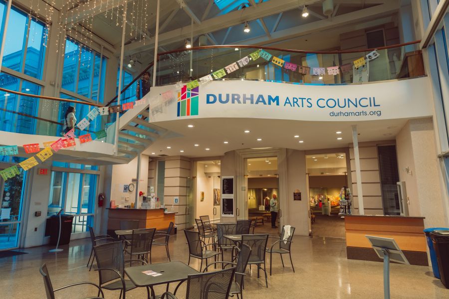The main lobby area of The Durham Arts Council displays a wide open area with chairs and tables.