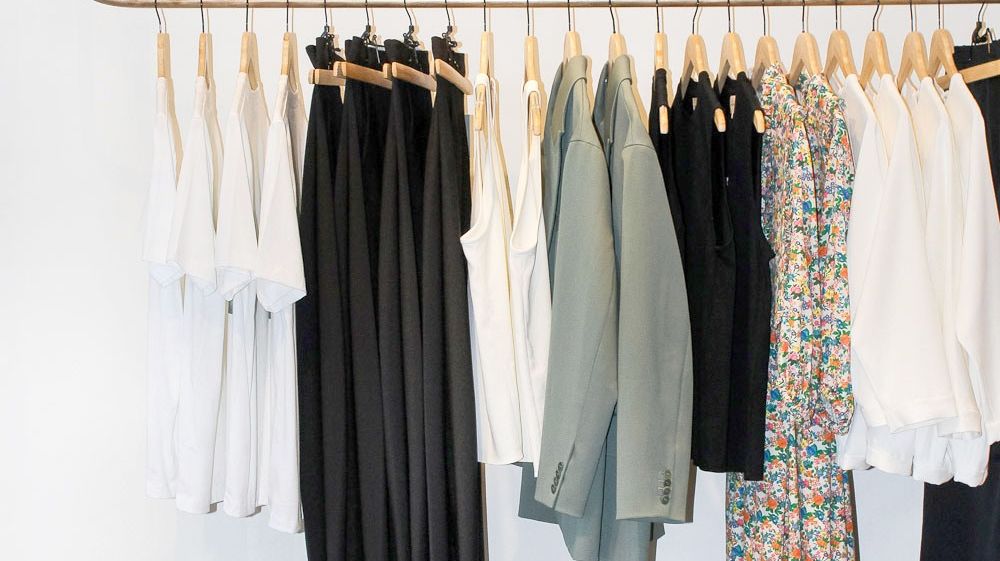 Earth toned clothes are lined up on a rack at Vert and Vogue in Durham, NC.