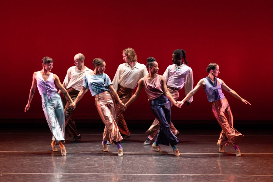 Performers dance in front of a red background on stage at the American Dance Festival.