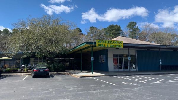 The Mediterranean Grill and Grocery Building stands under a blue sky as clouds roll by.