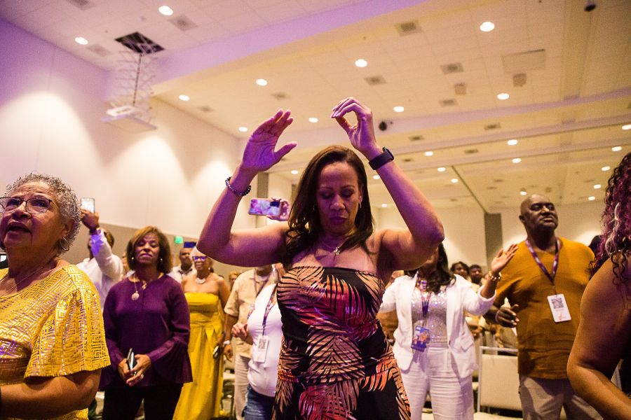 A woman dancing in a room among a crowd of attendees at the Marcus Anderson Jazz and Coffee Escape.
