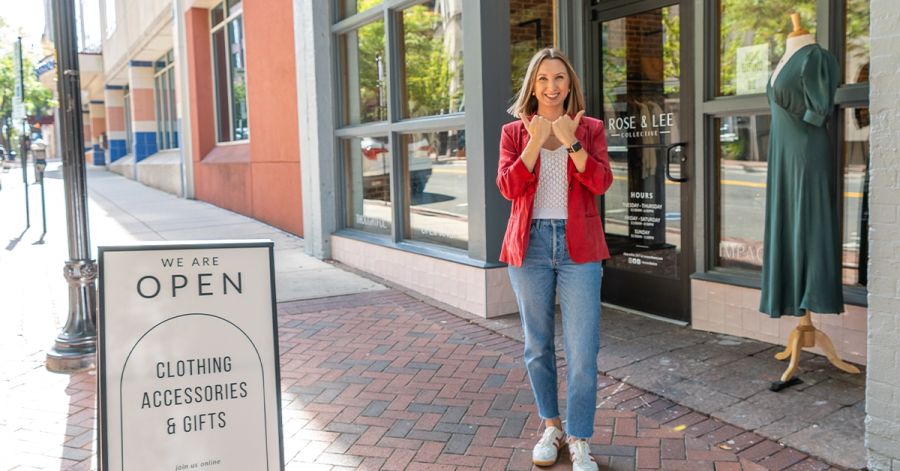 Amber Brennan, co-owner of Rose and Lee Collective, holds her hands in the shape of bull horns in front of her store.
