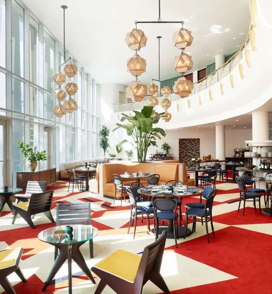 The lobby of The Durham Hotel features bold, geometrically shaped carpet, chandeliers and a wall of windows.